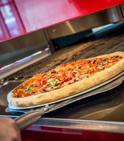 Versgebakken pizza wordt uit een professionele oven gehaald